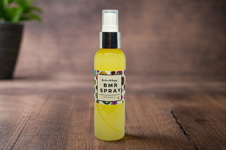 BMR Spray by House of Sheelaa in a bright yellow spray bottle with floral label, displayed on a wooden surface in a warm lifestyle setting.